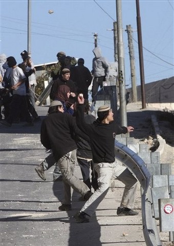 Masked Jewish settlers throw stones at Palestinian houses in the West Bank city of Hebron, Tuesday, Dec. 2, 2008. Dozens of Jewish settlers rioted Tuesday in the West Bank town of Hebron, clashing with the Israeli troops who guard them but who may also soon evict them from a disputed building they