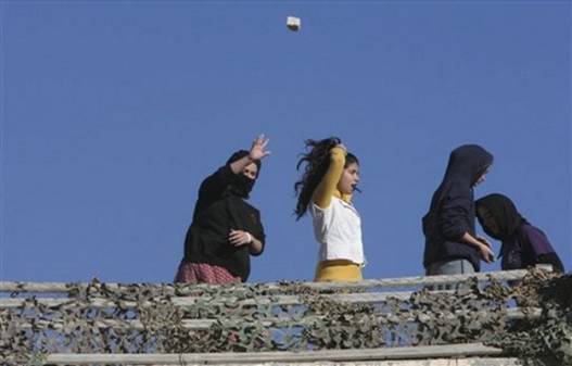 A Jewish settler throws a stone from a rooftop overlooking Palestinian houses in the West Bank city of Hebron, Tuesday, Dec. 2, 2008. Dozens of Jewish settlers rioted Tuesday in the West Bank town of Hebron, clashing with the Israeli troops who guard them but who may also soon evict them from a disputed building they