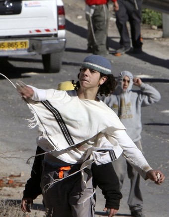 A Jewish settler (C) throws stones at Palestinian houses in the West Bank city of Hebron December 2, 2008. Jewish settlers and Palestinians threw stones in clashes on Monday and Tuesday that injured five in Hebron where Jews want to stop the eviction of 13 settler families, witnesses said. Hundreds of settler supporters, mostly youths, have come to the Jewish enclave in the past week to try to prevent the evacuation of a disputed building, raising tensions. From Reuters Pictures by REUTERS.