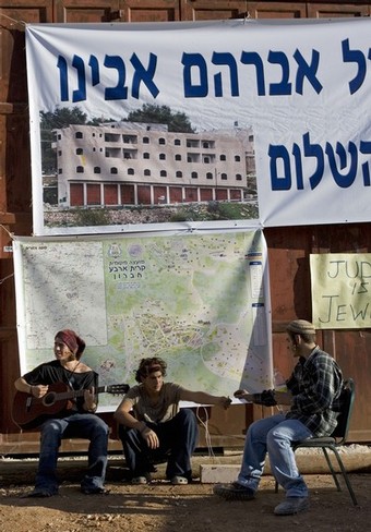 Jewish settlers play guitar in front of a disputed house occupied by settlers in the divided West Bank city of Hebron on November 23, 2008. About 100 Jewish settlers last week defied a High Court order to evacuate the house in the flashpoint West Bank city of Hebron, and braced for possible confrontation with police. The court rejected an appeal by two rightwing organisations against an order issued by the state to evacuate the Hebron house, which the settlers claim they had purchased from a Palestinian, who denies selling the house. The controversial house was occupied by dozens of hardline Jewish settlers in March 2007. They have remained in the four-storey building which they dubbed 